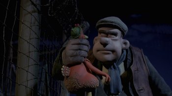Movie still from “Chicken Run” (2000), directed by Peter Lord – A statue of a man holding an object in his hand; Close Up shot, Low angle