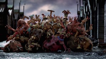 Movie still from “Chicken Run” (2000), directed by Peter Lord – A group of people that are sitting in the dirt; Wide shot, High angle