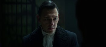 Movie still from “Chilling Adventures of Sabrina” (2018), created by Roberto Aguirre-Sacasa – A person wearing a suit and tie; Close Up shot, Over the shoulder angle