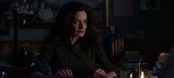 Movie still from “Chilling Adventures of Sabrina” (2018), created by Roberto Aguirre-Sacasa – A woman sitting in a chair in a dark room; Close Up shot, Over the shoulder angle