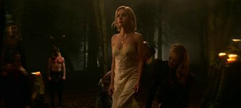 Movie still from “Chilling Adventures of Sabrina” (2018), created by Roberto Aguirre-Sacasa – A woman in a white dress walking in the woods; Medium shot, Low angle