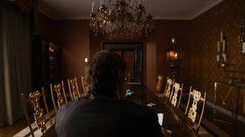 Movie still from “Better Call Saul” (2015), created by Vince Gilligan – A man sitting in front of a long wooden table; Medium shot, Over the shoulder angle