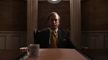 Movie still from “Better Call Saul” (2015), created by Vince Gilligan – A man sitting at a table in front of a coffee mug; Medium shot, Low angle