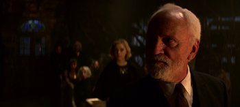 Movie still from “Chilling Adventures of Sabrina” (2018), created by Roberto Aguirre-Sacasa – An old man with a beard is looking into the camera; Close Up shot, Over the shoulder angle
