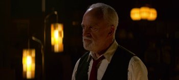 Movie still from “Chilling Adventures of Sabrina” (2018), created by Roberto Aguirre-Sacasa – An older man wearing a vest and a red tie; Medium shot, Over the shoulder angle