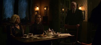 Movie still from “Chilling Adventures of Sabrina” (2018), created by Roberto Aguirre-Sacasa – A woman sitting at a table with a tea pot; Medium shot, Over the shoulder angle