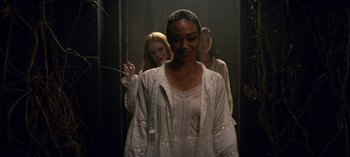 Movie still from “Chilling Adventures of Sabrina” (2018), created by Roberto Aguirre-Sacasa – A woman in a white dress standing next to two other women; Medium shot, Over the shoulder angle