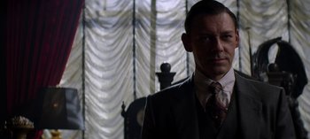 Movie still from “Chilling Adventures of Sabrina” (2018), created by Roberto Aguirre-Sacasa – A man in a suit and tie in front of a window; Close Up shot, Low angle