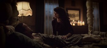 Movie still from “Chilling Adventures of Sabrina” (2018), created by Roberto Aguirre-Sacasa – A woman standing next to a man laying in a bed; Medium shot, Over the shoulder angle