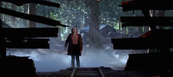 Movie still from “Chilling Adventures of Sabrina” (2018), created by Roberto Aguirre-Sacasa – A woman standing on a train track in the middle of a forest; Wide shot, Low angle