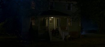 Movie still from “Chilling Adventures of Sabrina” (2018), created by Roberto Aguirre-Sacasa – Two people sitting on the steps of a house at night; Extreme Wide shot, High angle