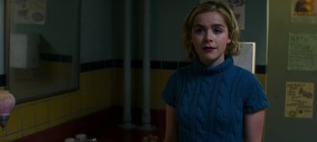Movie still from “Chilling Adventures of Sabrina” (2018), created by Roberto Aguirre-Sacasa – A woman in a blue sweater standing in a room; Close Up shot, Over the shoulder angle
