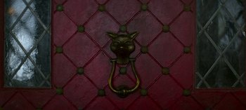 Movie still from “Chilling Adventures of Sabrina” (2018), created by Roberto Aguirre-Sacasa – A door knocker on a red wall; Extreme Close Up shot, Overhead angle