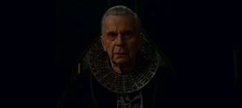 Movie still from “Chilling Adventures of Sabrina” (2018), created by Roberto Aguirre-Sacasa – An older man wearing a black and white collar; Close Up shot, Low angle
