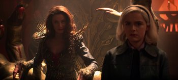 Movie still from “Chilling Adventures of Sabrina” (2018), created by Roberto Aguirre-Sacasa – Two women standing next to each other in front of a wall; Medium shot, Over the shoulder angle
