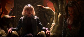 Movie still from “Chilling Adventures of Sabrina” (2018), created by Roberto Aguirre-Sacasa – A woman sitting in front of a statue of a demon; Medium shot, High angle