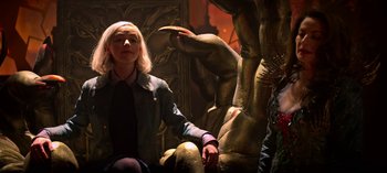 Movie still from “Chilling Adventures of Sabrina” (2018), created by Roberto Aguirre-Sacasa – A woman sitting on a chair next to a statue; Medium shot, Low angle
