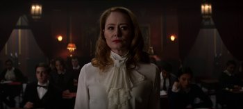 Movie still from “Chilling Adventures of Sabrina” (2018), created by Roberto Aguirre-Sacasa – A woman in a white blouse standing in front of a group of people; Close Up shot, Over the shoulder angle