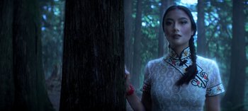 Movie still from “Chilling Adventures of Sabrina” (2018), created by Roberto Aguirre-Sacasa – A woman in a white dress standing next to a tree in the woods; Close Up shot, Low angle