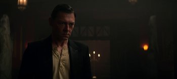 Movie still from “Chilling Adventures of Sabrina” (2018), created by Roberto Aguirre-Sacasa – A man standing in a dark room with a candle; Close Up shot, Low angle