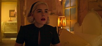 Movie still from “Chilling Adventures of Sabrina” (2018), created by Roberto Aguirre-Sacasa – A woman with blonde hair is sitting in front of a lamp; Close Up shot, Over the shoulder angle