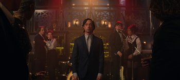 Movie still from “Chilling Adventures of Sabrina” (2018), created by Roberto Aguirre-Sacasa – A man in a suit standing in front of a group of people; Medium shot, Low angle