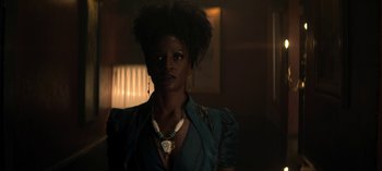 Movie still from “Chilling Adventures of Sabrina” (2018), created by Roberto Aguirre-Sacasa – A woman with a necklace in a dark room; Close Up shot, Low angle