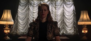 Movie still from “Chilling Adventures of Sabrina” (2018), created by Roberto Aguirre-Sacasa – A woman in a black and white dress stands in front of a window; Medium shot, Low angle