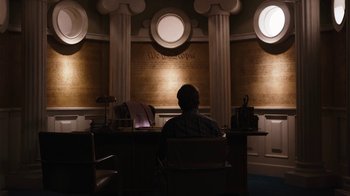 Movie still from “Better Call Saul” (2015), created by Vince Gilligan – A man sitting at a desk in front of a wall with the constitution on it; Wide shot, Over the shoulder angle