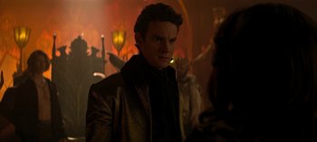 Movie still from “Chilling Adventures of Sabrina” (2018), created by Roberto Aguirre-Sacasa – A man standing in front of a group of people; Close Up shot, Over the shoulder angle