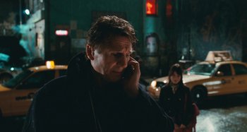 Movie still from “Chloe” (2009), directed by Atom Egoyan – A man talking on a cell phone while standing next to a woman; Close Up shot, Over the shoulder angle