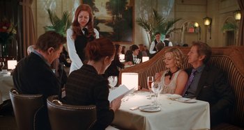 Movie still from “Chloe” (2009), directed by Atom Egoyan – A woman standing at a table in front of two other women; Medium shot, Over the shoulder angle