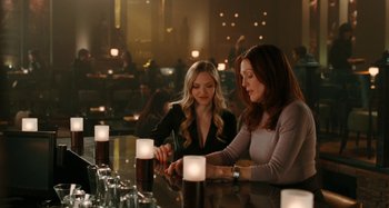 Movie still from “Chloe” (2009), directed by Atom Egoyan – Two women are sitting at a bar with candles on the table; Medium shot, Over the shoulder angle