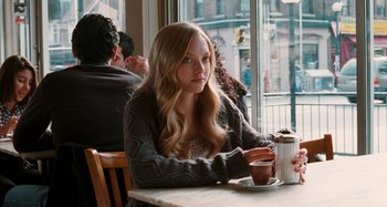 Movie still from “Chloe” (2009), directed by Atom Egoyan – A woman sitting at a table with a cup of coffee in front of a window; Medium shot, Over the shoulder angle