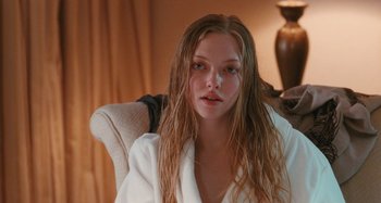 Movie still from “Chloe” (2009), directed by Atom Egoyan – A beautiful young lady sitting in a chair wearing a white robe; Close Up shot, Over the shoulder angle