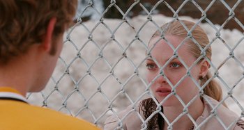 Movie still from “Chloe” (2009), directed by Atom Egoyan – A woman looking through a chain link fence; Close Up shot, Over the shoulder angle