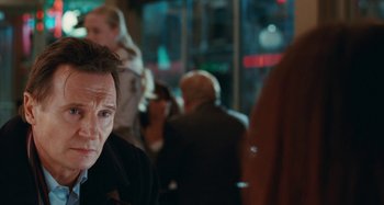 Movie still from “Chloe” (2009), directed by Atom Egoyan – A man sitting in a crowd of people at night; Close Up shot, Over the shoulder angle