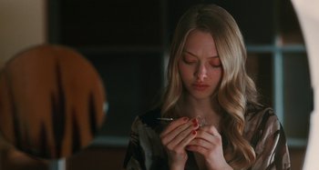 Movie still from “Chloe” (2009), directed by Atom Egoyan – A woman is smoking a cigarette while holding a cell phone in her hands; Close Up shot, High angle