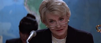Movie still from “Clear and Present Danger” (1994), directed by Phillip Noyce – An older woman wearing glasses and a black jacket; Close Up shot, Over the shoulder angle