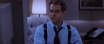 Movie still from “Clear and Present Danger” (1994), directed by Phillip Noyce – A man wearing a tie and suspenders sitting on a couch; Close Up shot, Low angle