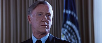 Movie still from “Clear and Present Danger” (1994), directed by Phillip Noyce – An older man wearing a suit and tie in front of an american flag; Close Up shot, Low angle