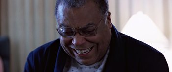 Movie still from “Clear and Present Danger” (1994), directed by Phillip Noyce – An older man wearing glasses and a jacket smiling; Close Up shot, Low angle