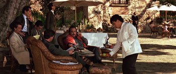 Movie still from “Clear and Present Danger” (1994), directed by Phillip Noyce – A group of people sitting around a table with food on it; Wide shot, Over the shoulder angle