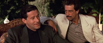 Movie still from “Clear and Present Danger” (1994), directed by Phillip Noyce – Two men in suits and ties , one of which has his arm around another man; Close Up shot, Low angle