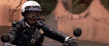 Movie still from “Clear and Present Danger” (1994), directed by Phillip Noyce – A police officer riding a motorcycle on the street; Medium shot, Low angle