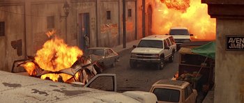 Movie still from “Clear and Present Danger” (1994), directed by Phillip Noyce – A street scene with cars on fire and a person walking on the sidewalk; Wide shot, High angle