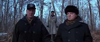 Movie still from “Clear and Present Danger” (1994), directed by Phillip Noyce – A man in a trench coat standing in front of two other men; Medium shot, Low angle