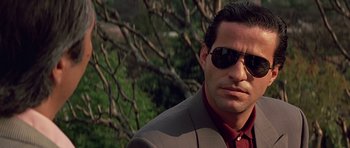 Movie still from “Clear and Present Danger” (1994), directed by Phillip Noyce – A person wearing a suit and sunglasses; Close Up shot, Low angle