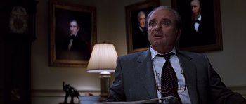 Movie still from “Clear and Present Danger” (1994), directed by Phillip Noyce – An older man wearing a suit and tie in front of a lamp; Medium shot, Low angle