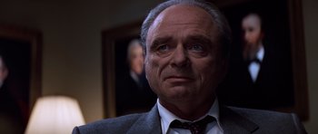 Movie still from “Clear and Present Danger” (1994), directed by Phillip Noyce – An older man wearing a suit and tie looking at the camera; Close Up shot, Low angle